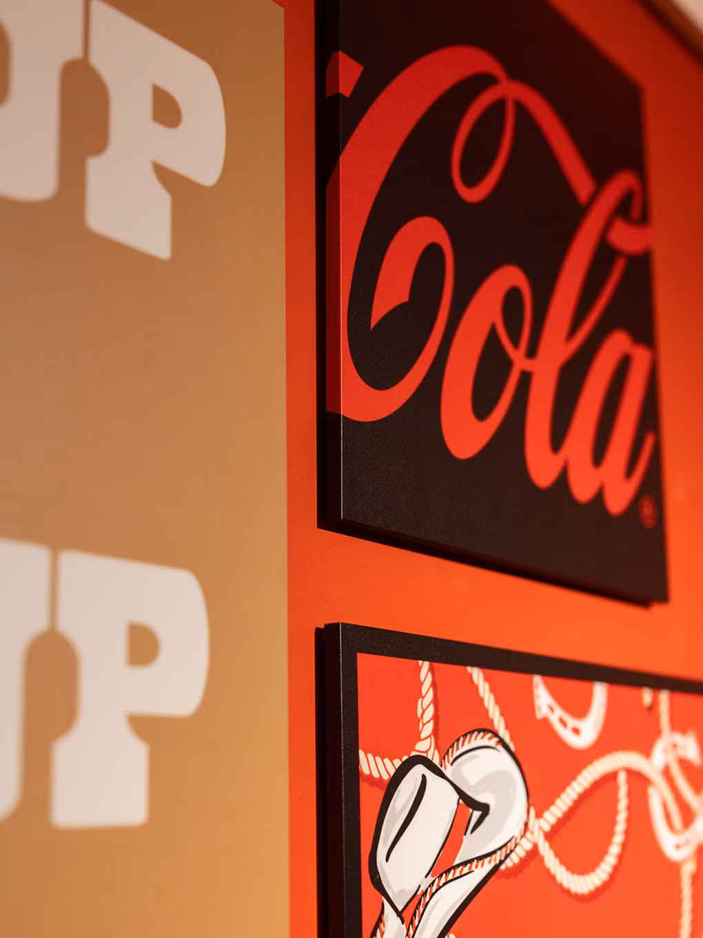 Detail shot of custom-fabricated Coca-Cola script and cowboy graphic panels on the Ink Studio wall.