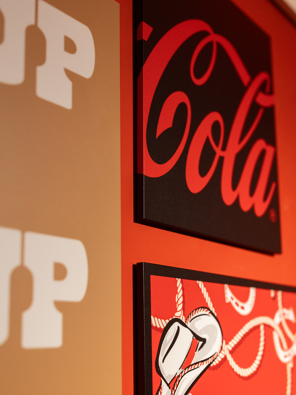Detail shot of custom-fabricated Coca-Cola script and cowboy graphic panels on the Ink Studio wall.