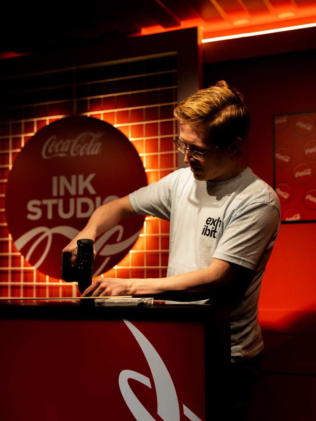 Exhibit Studio fabricator finishing custom signage details on the Coca-Cola Ink Studio build.