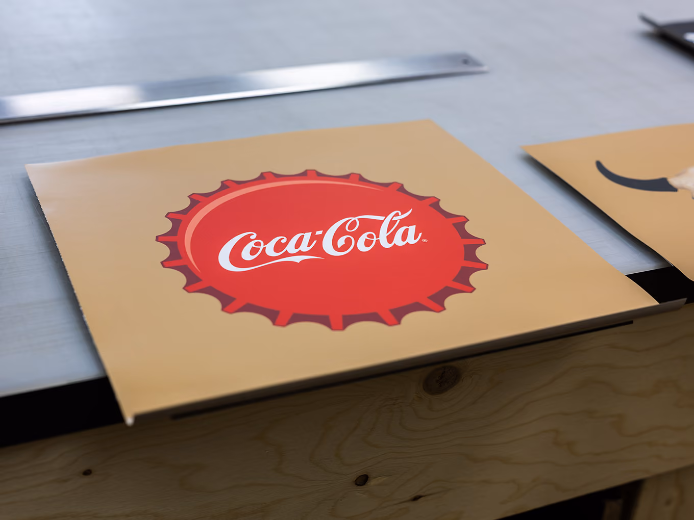 Freshly printed Coca-Cola bottle cap graphic panel staged for fabrication at Exhibit Studio.