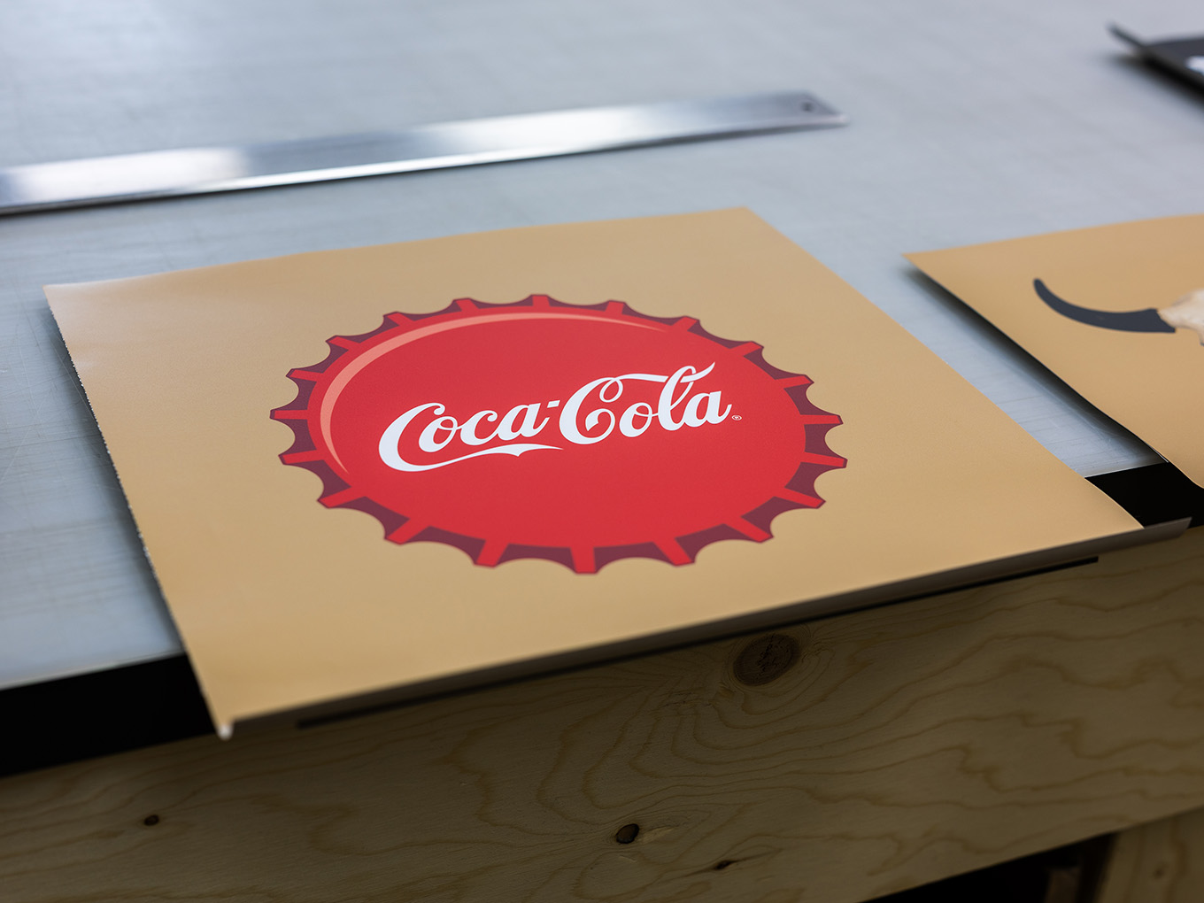 Freshly printed Coca-Cola bottle cap graphic panel staged for fabrication at Exhibit Studio.