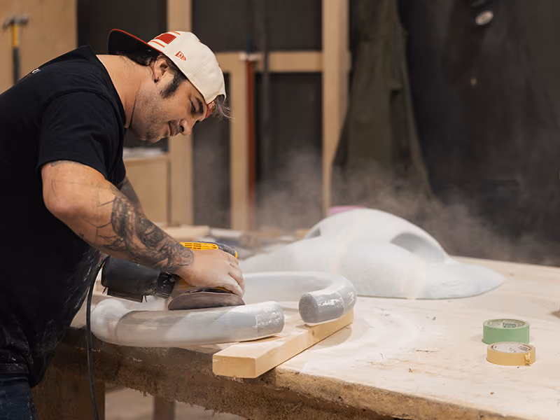 Exhibit Studio fabricator sanding a custom-shaped foam component for the GMC parade vehicle display.