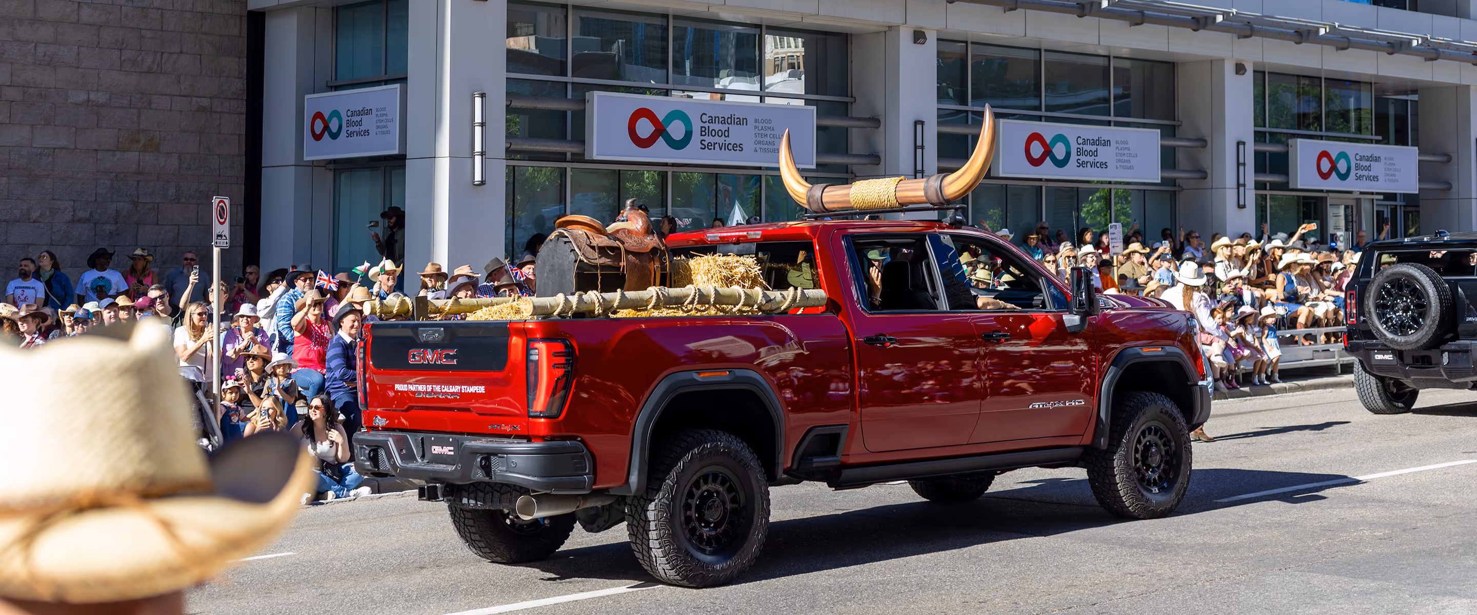 Custom GMC parade truck with oversized steer horns and saddle display driving in the Calgary Stampede parade.