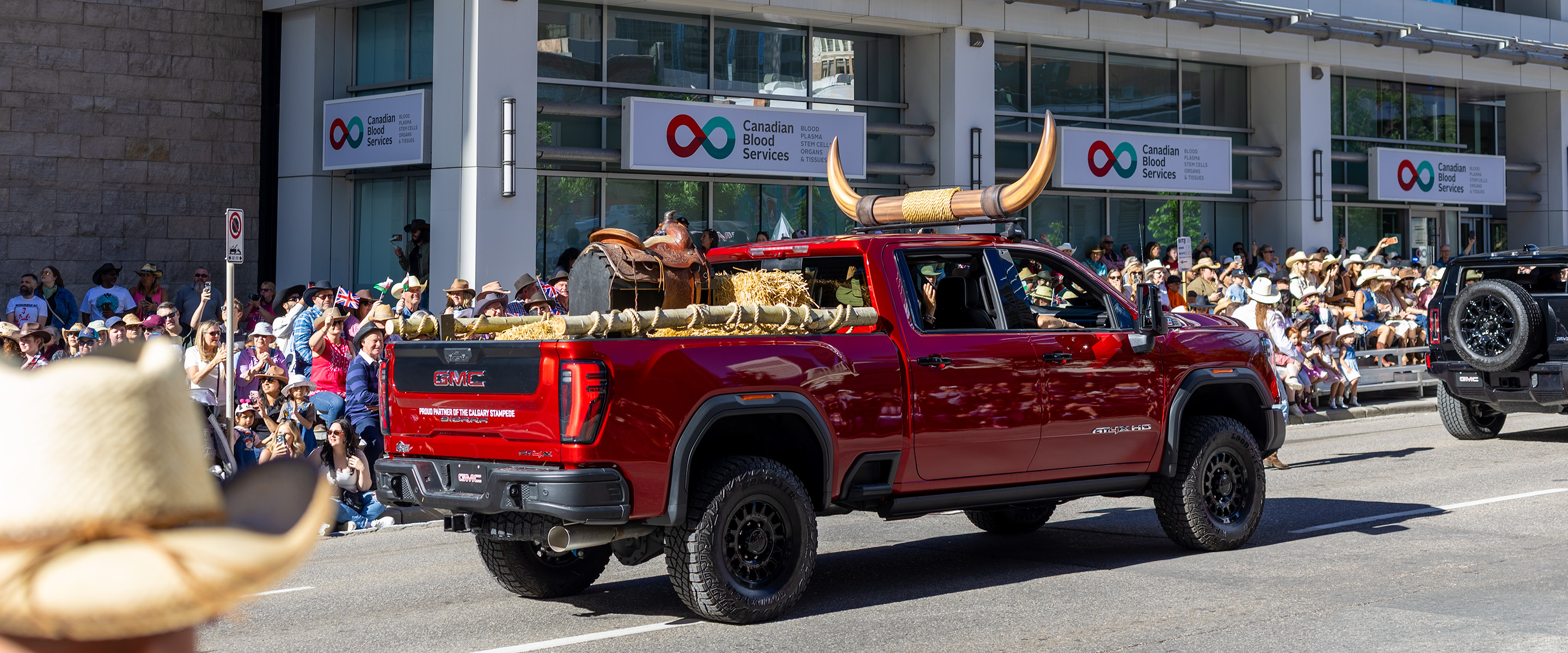 Custom GMC parade truck with oversized steer horns and saddle display driving in the Calgary Stampede parade.