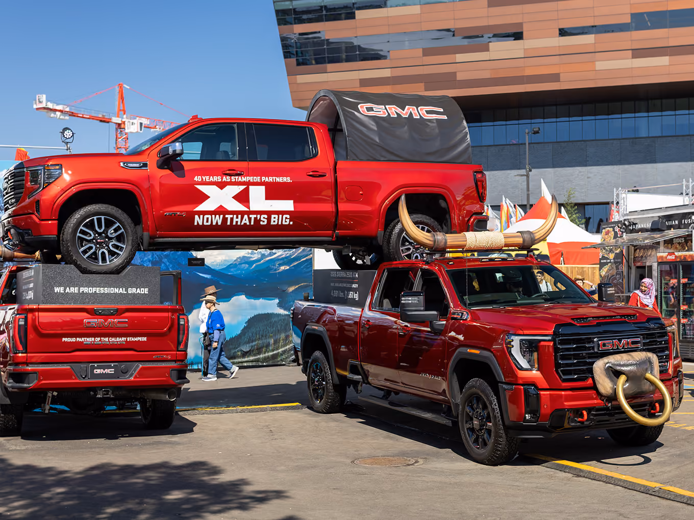 Custom GMC truck display with fabricated bull horns positioned beside a second stacked GMC parade vehicle.