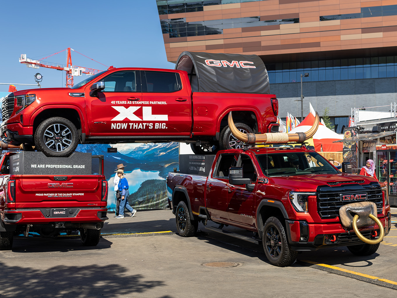 Custom GMC truck display with fabricated bull horns positioned beside a second stacked GMC parade vehicle.