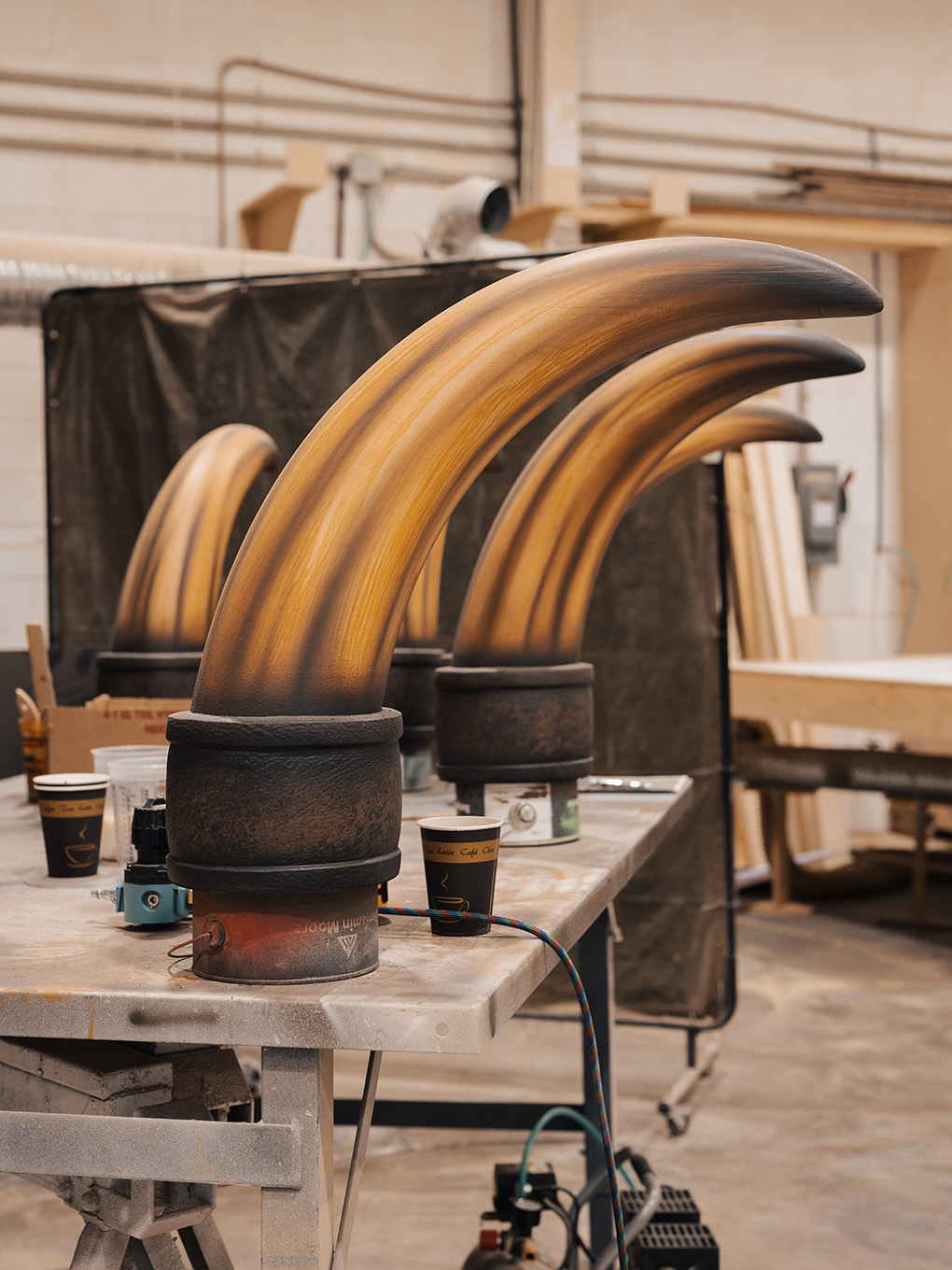 Set of finished custom horn sculptures with bronze wood-grain finish staged in the Exhibit Studio shop.