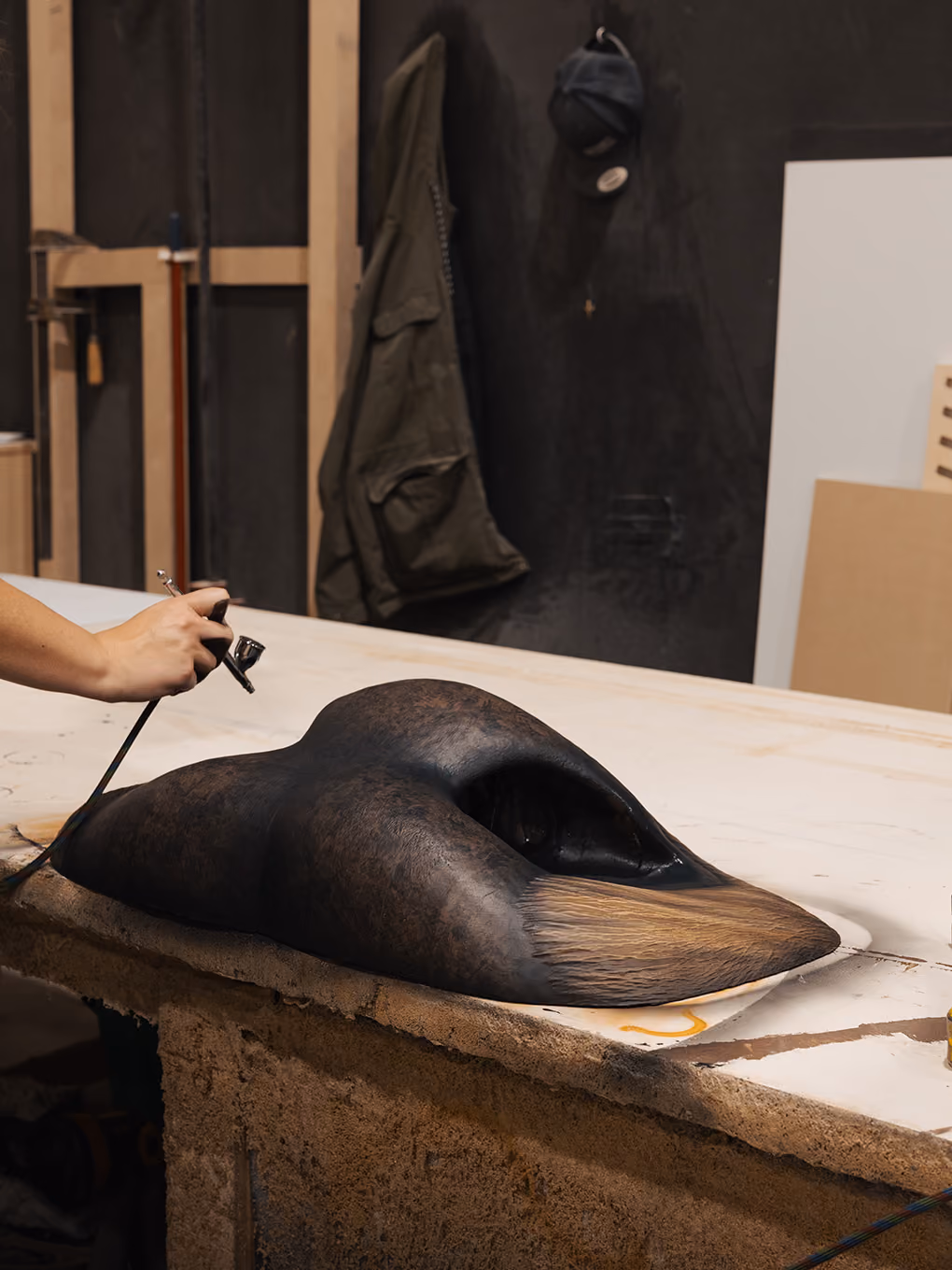 Fabricator airbrushing a hide-like texture onto the custom bull nose sculpture for the GMC display.