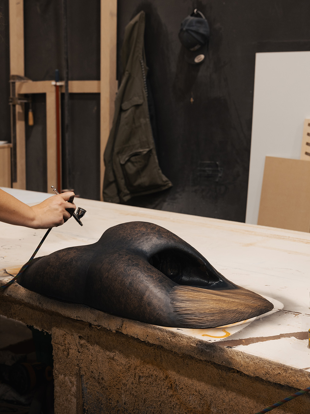 Fabricator airbrushing a hide-like texture onto the custom bull nose sculpture for the GMC display.