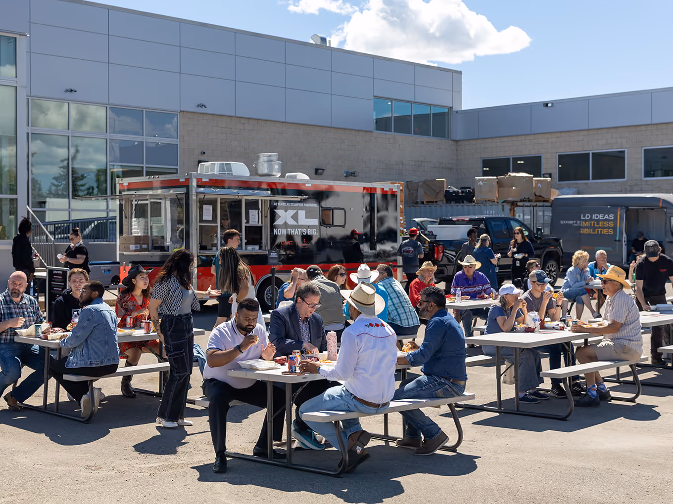 Guests enjoy a Stampede lunch at a GMC dealer derby event beside a branded GMC XL food truck.
