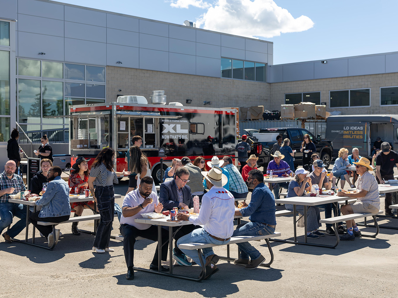 Guests enjoy a Stampede lunch at a GMC dealer derby event beside a branded GMC XL food truck.