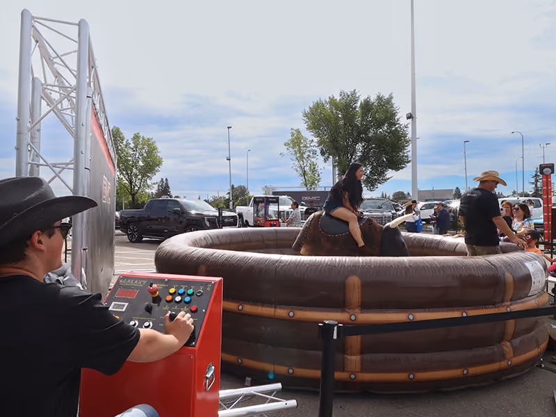 Operator controls the mechanical bull ride as a guest takes a turn at the GMC Stampede event.
