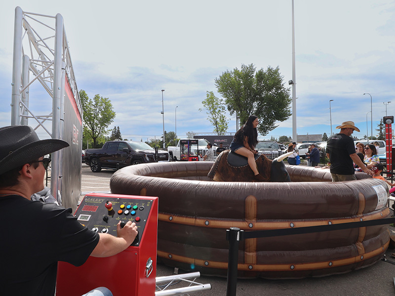 Operator controls the mechanical bull ride as a guest takes a turn at the GMC Stampede event.
