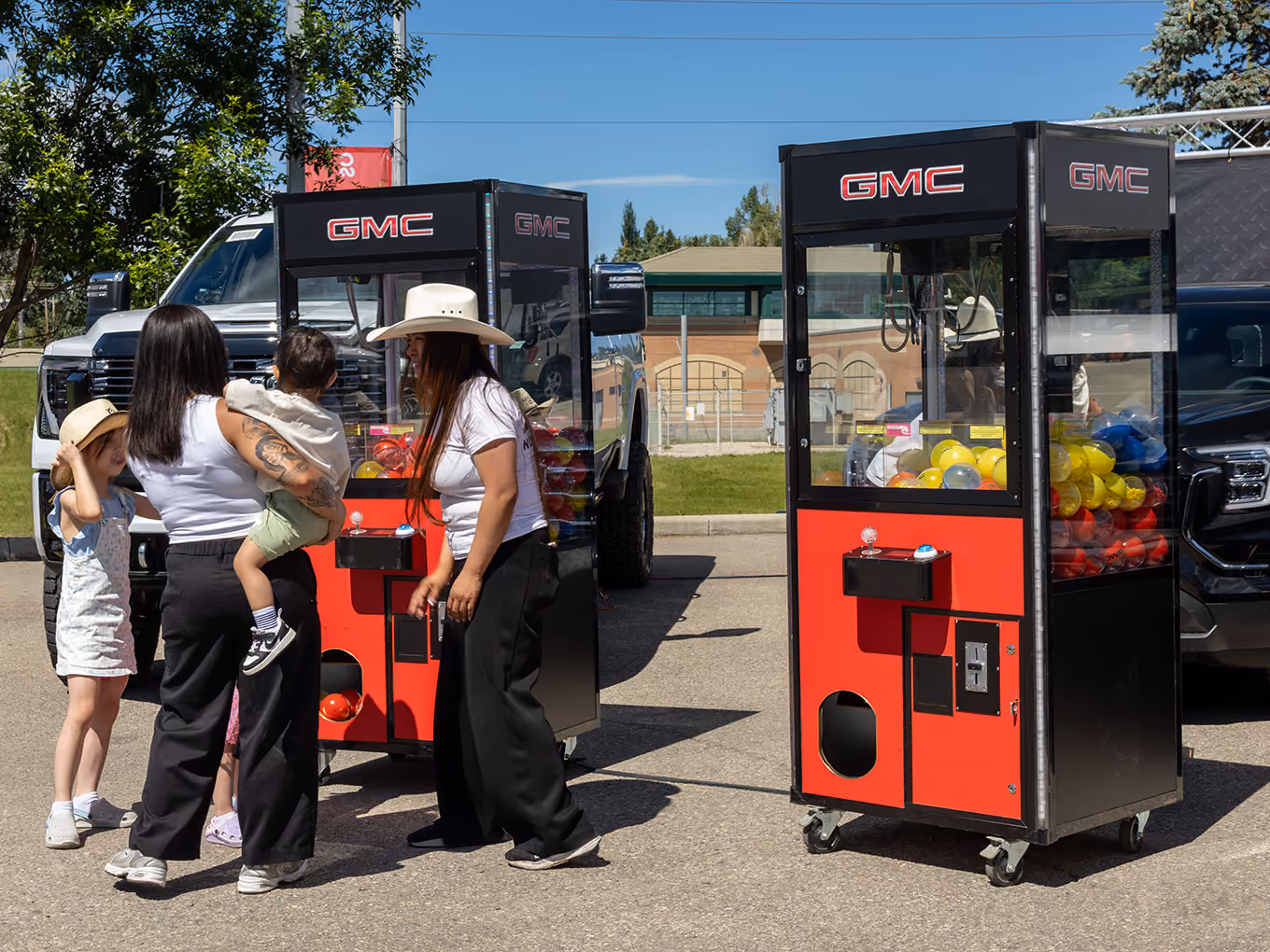 Families play custom GMC-branded claw machine games at a Calgary Stampede event.