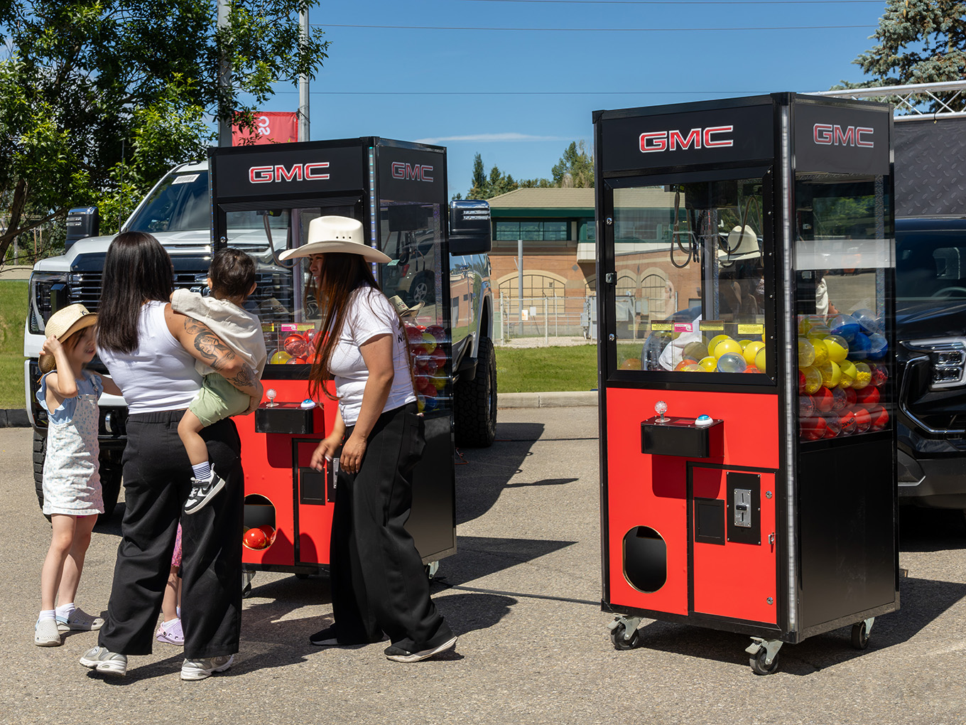 Families play custom GMC-branded claw machine games at a Calgary Stampede event.