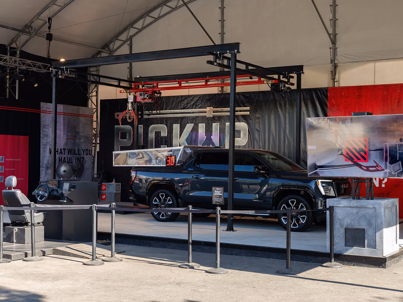 Custom oversized claw machine built from a crane and GMC truck bed staged under a Stampede activation tent.
