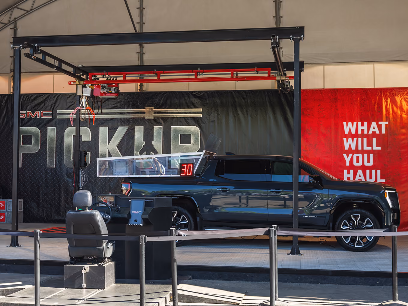 Custom oversized claw machine built from a crane and GMC truck bed challenges guests to retrieve prize boxes using the control station.