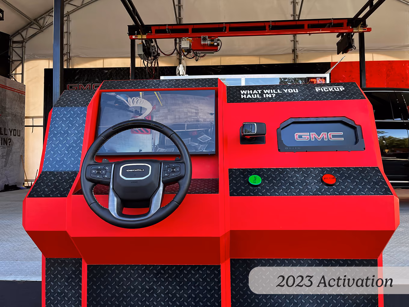 2023 GMC claw machine control station with steering wheel, live-view monitor, and start button.
