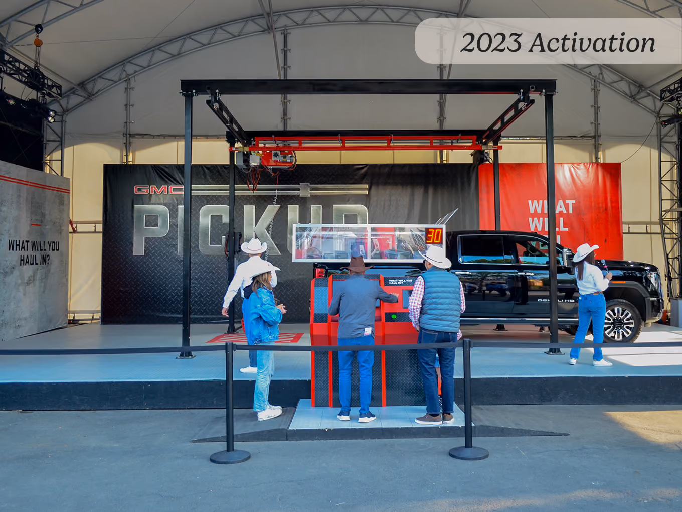 023 guests play the GMC claw machine game beneath a truss-mounted crane at the Calgary Stampede.