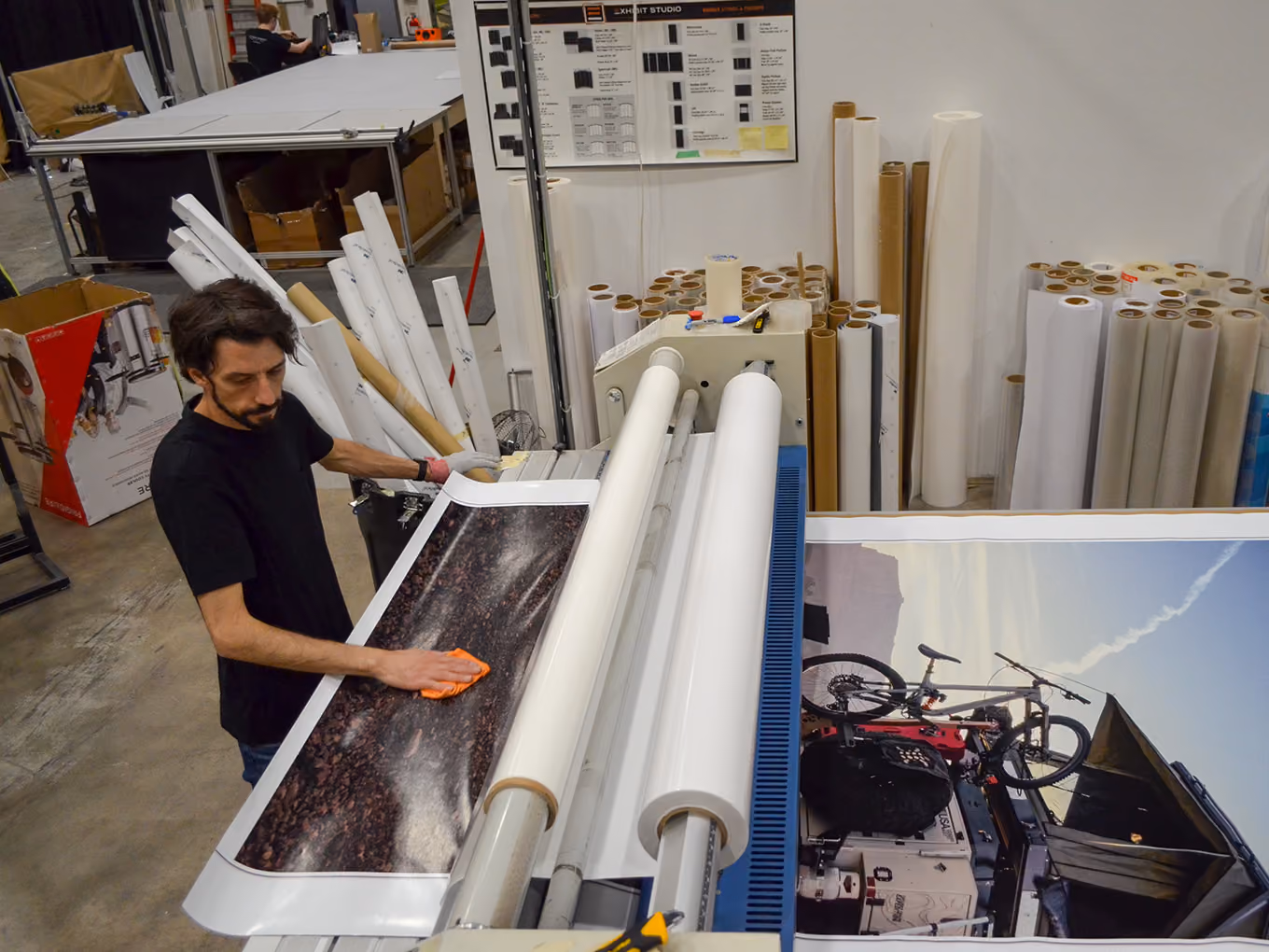 Exhibit Studio production staff finishing a large-format printed graphic panel in the shop.