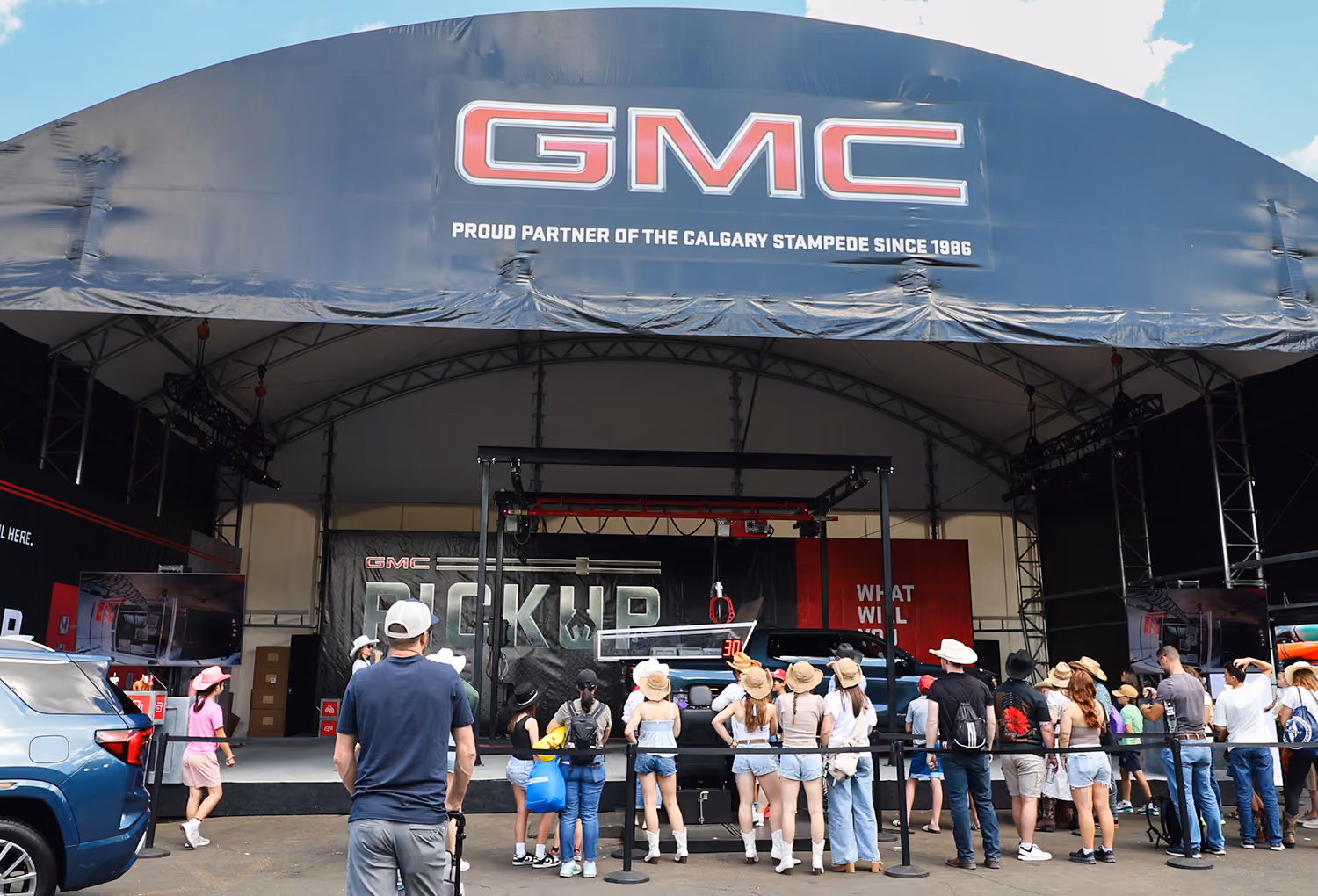 Guests line up beneath the branded GMC midway tent to play the claw machine game.