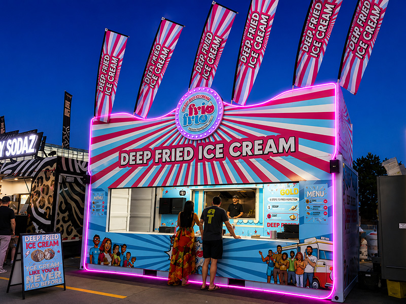 The Frio Frio stand at night, outlined in glowing pink LED lighting, as customers order at the service window.