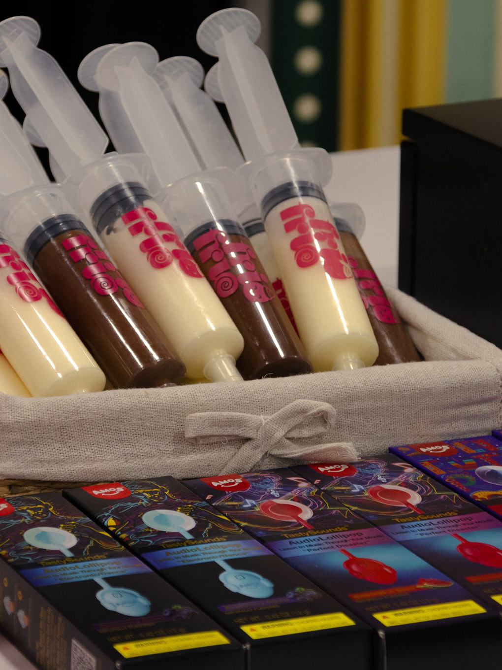 Frio Frio-branded syringes filled with milk and white chocolate, arranged in a basket.