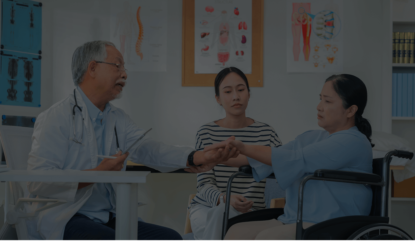 Doctor examining the pulse of a woman in a wheelchair while a younger woman watches attentively in a medical office.