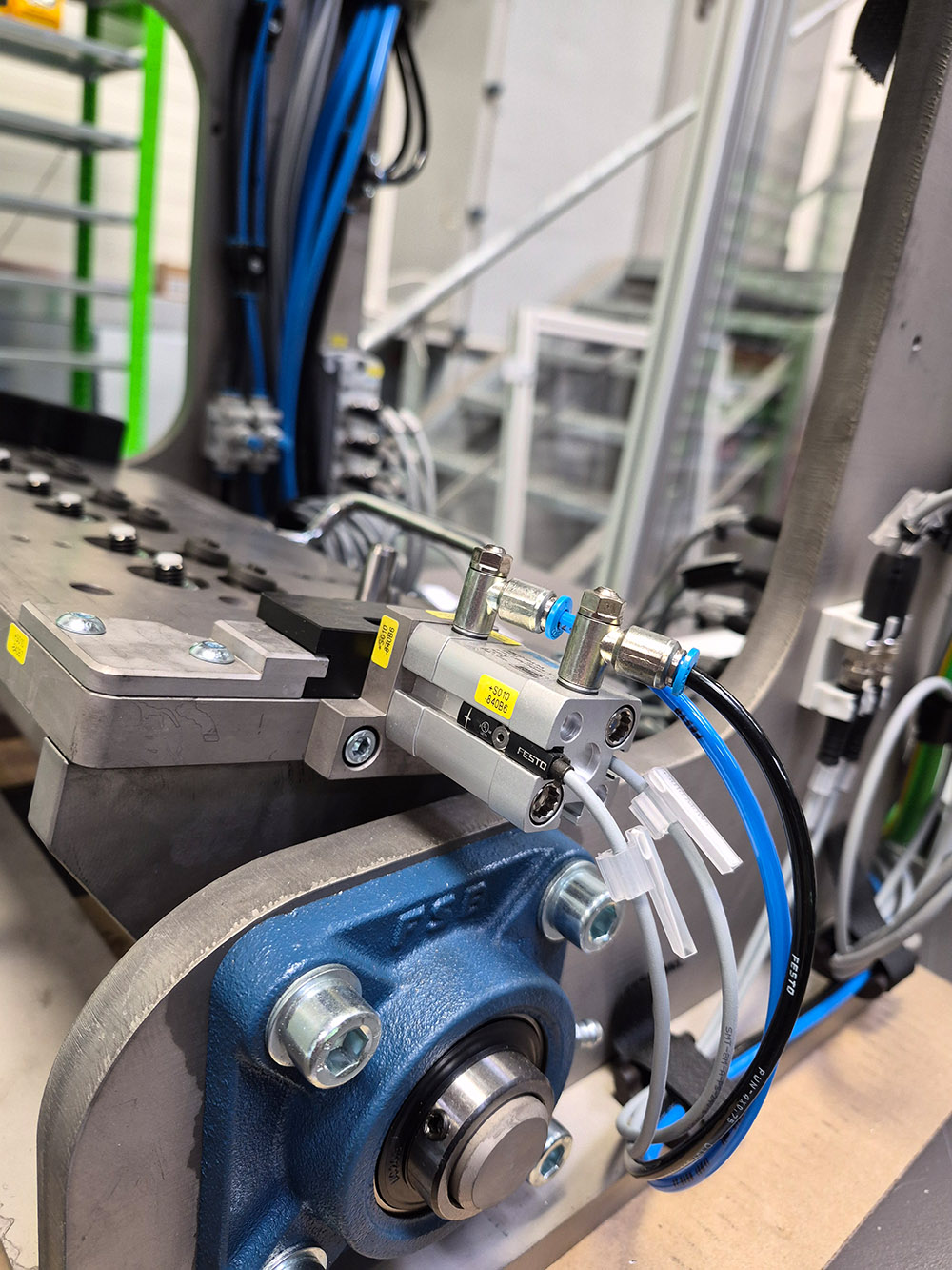Nahaufnahme eines blauen Kugellagergehäuses mit angeschlossenen pneumatischen Schläuchen und Metallteilen