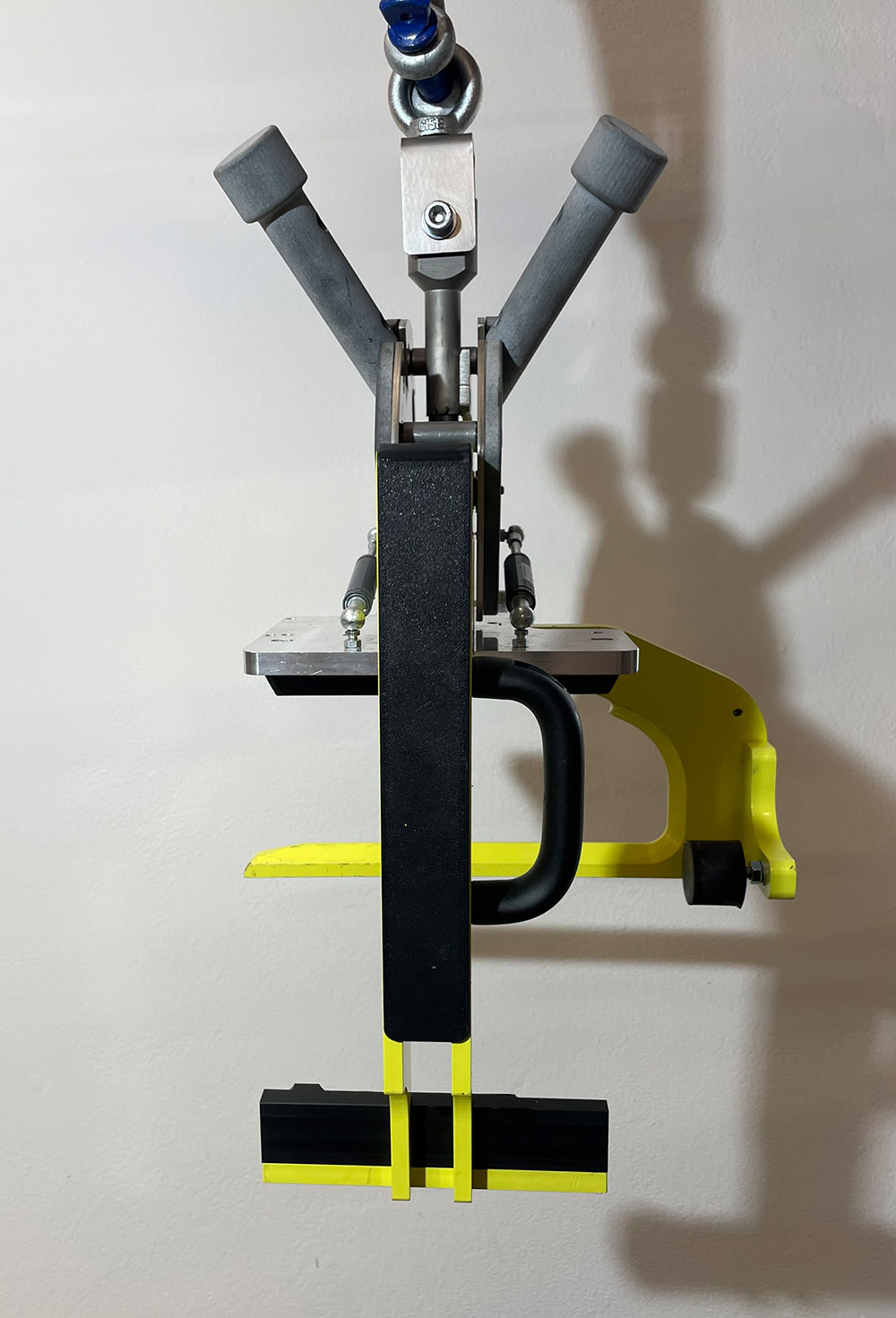 Fahrradhalterung mit grauen Griffen und gelben Halteelementen an weißer Wand.