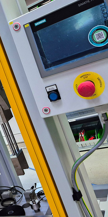 Siemens Steuerung mit Bildschirm und rotem Not-Aus-Knopf an industrieller Maschine.