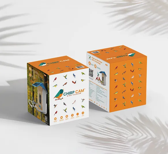 Two Chirp Cam bird feeder product boxes with colorful bird illustrations on an orange and white background, casting shadows on a light surface.
