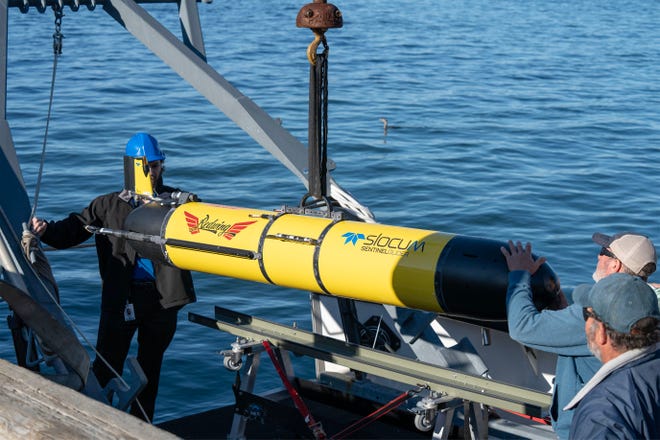 Teledyne's Garrett Miller, left, and SMELTS Ocean Explorer captain Kevin Rand, right, guide the Redwing glider to the dock for a kick off ceremony for the round the world Sentinel Mission at the Woods Hole Oceanographic Docks. Photo taken on Oct. 10, 2025