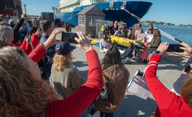 Rutgers Executive Dean of the school of Environmental and Biological Sciences, Laura Lawson, left, joins the crowd photographing her students and staff circling the Redwing robotic autonomous underwater glider before it heads out on the Sentinel Mission. Photo taken on Oct. 10, 2025