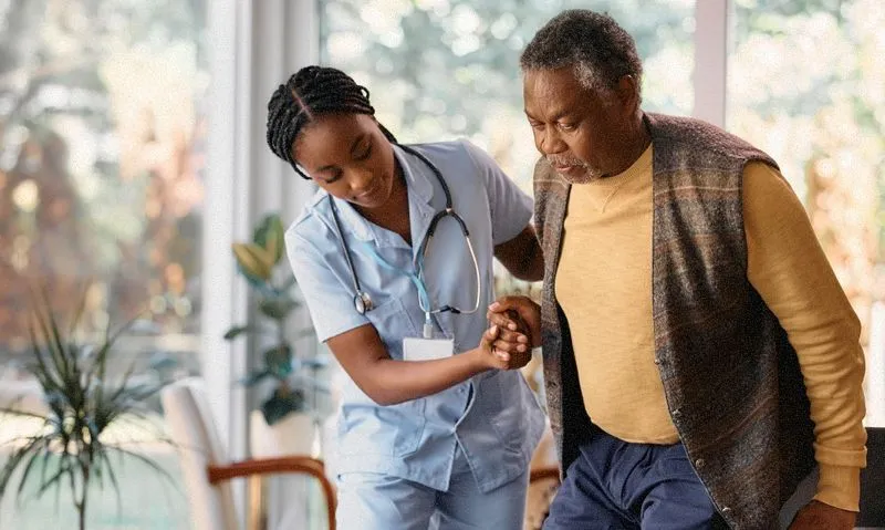 a nurse helping an older person move to a wheelchair