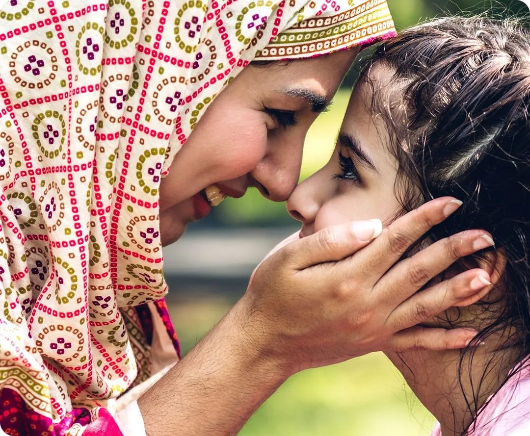 A muslim mother pushing her forehead to her child's forehead.
