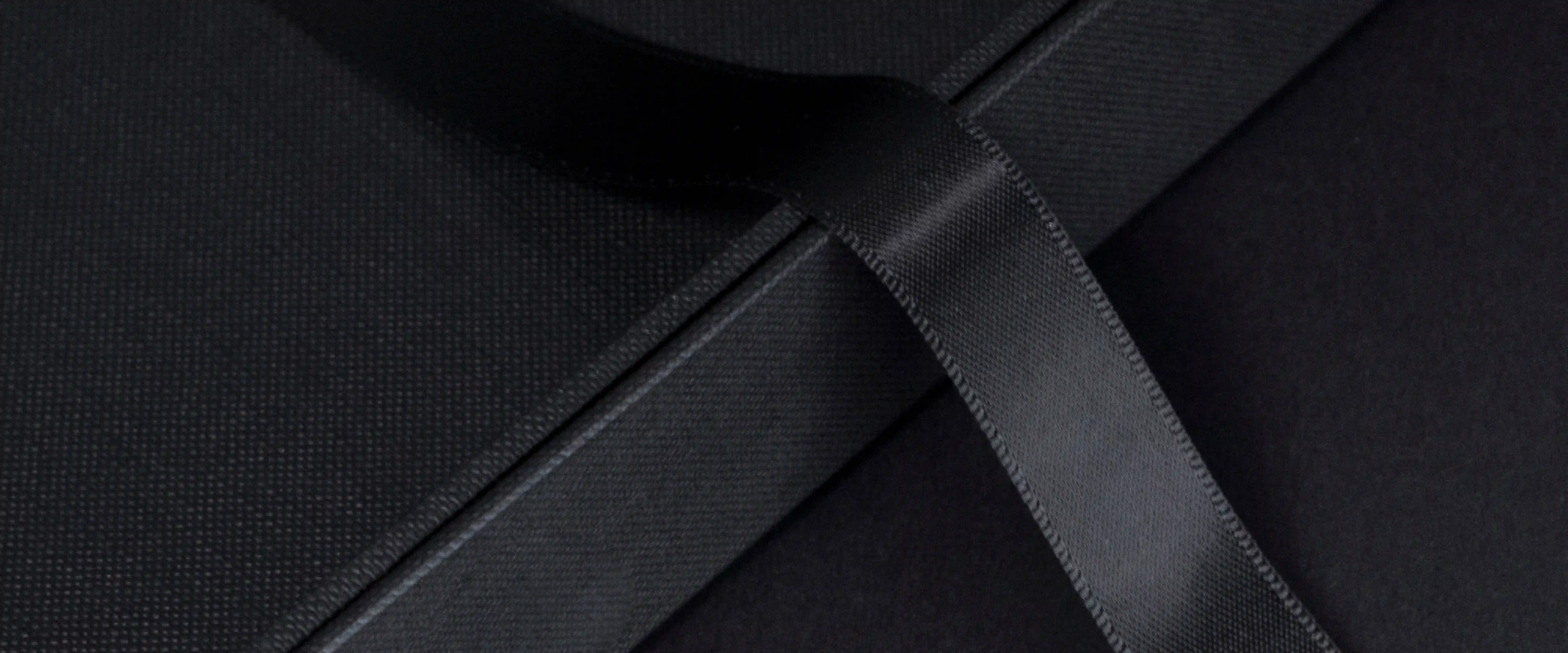 Détail d'une couverture noire texturée et de son ruban de satin