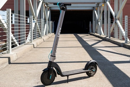 Levy electric scooter parked on a sunlit concrete pathway with metal railings on both sides.