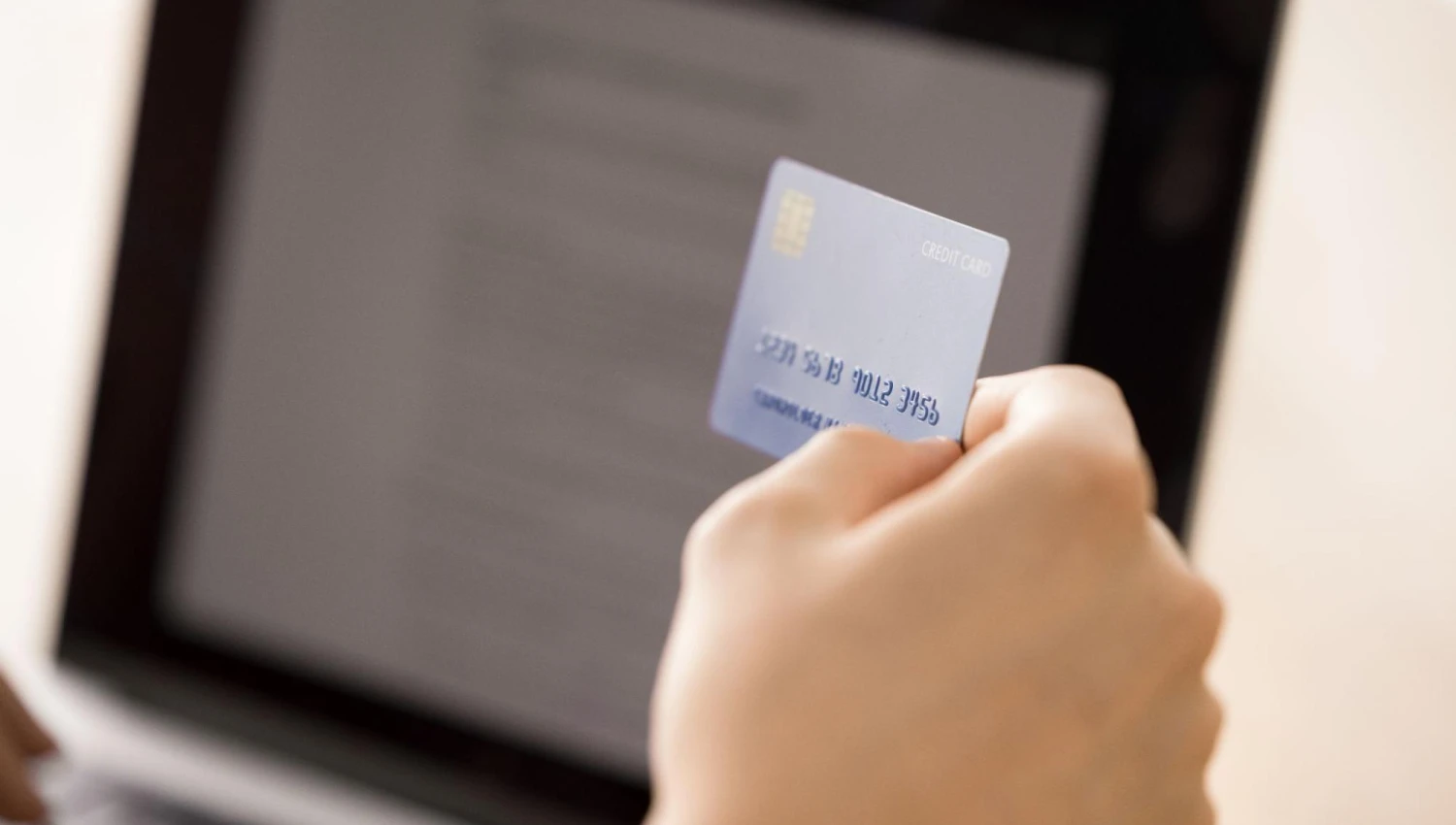 A close-up of a hand with a credit card ready to make an online order