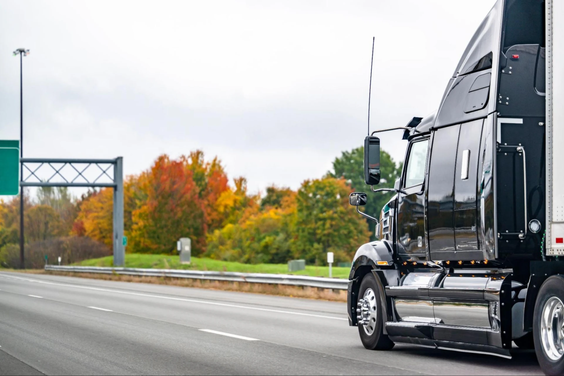 Industrial black long haul big rig high cab semi truck tractor transporting cargo