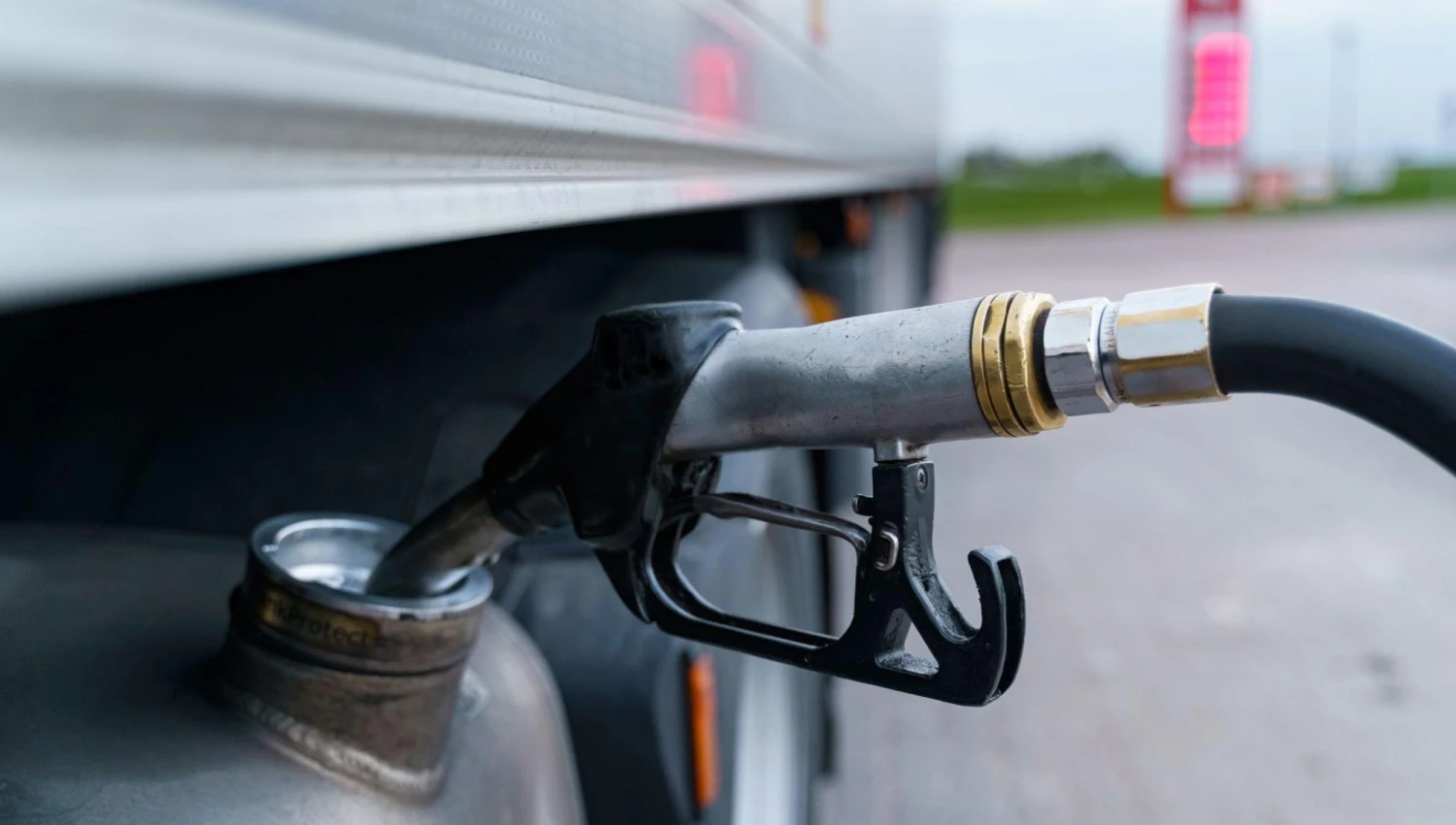 A close-up of a gas station gun inserted into the fuel tank