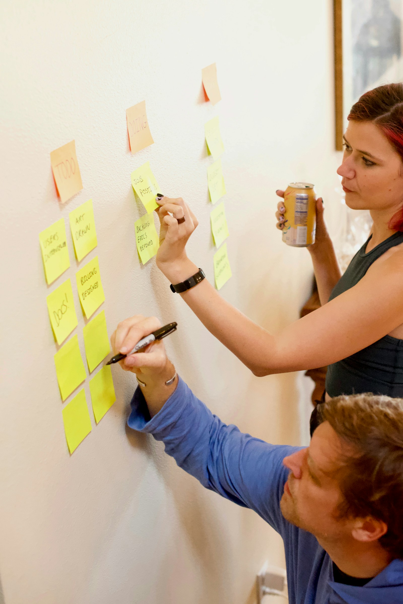 Två personer skriver på post-it-lappar på en vägg