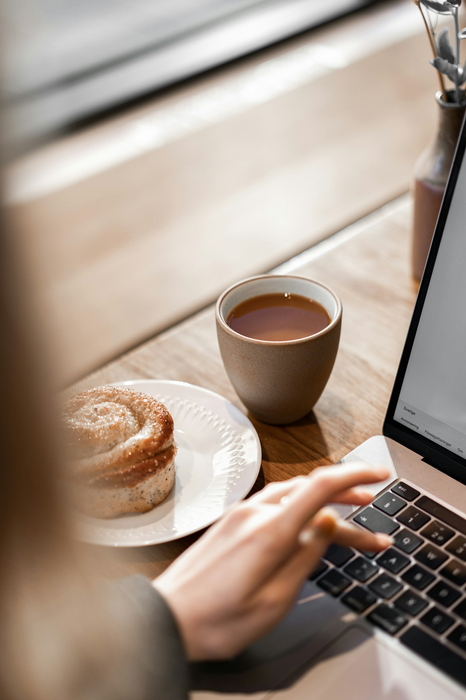 Person som skriver på en laptop bredvid en kopp