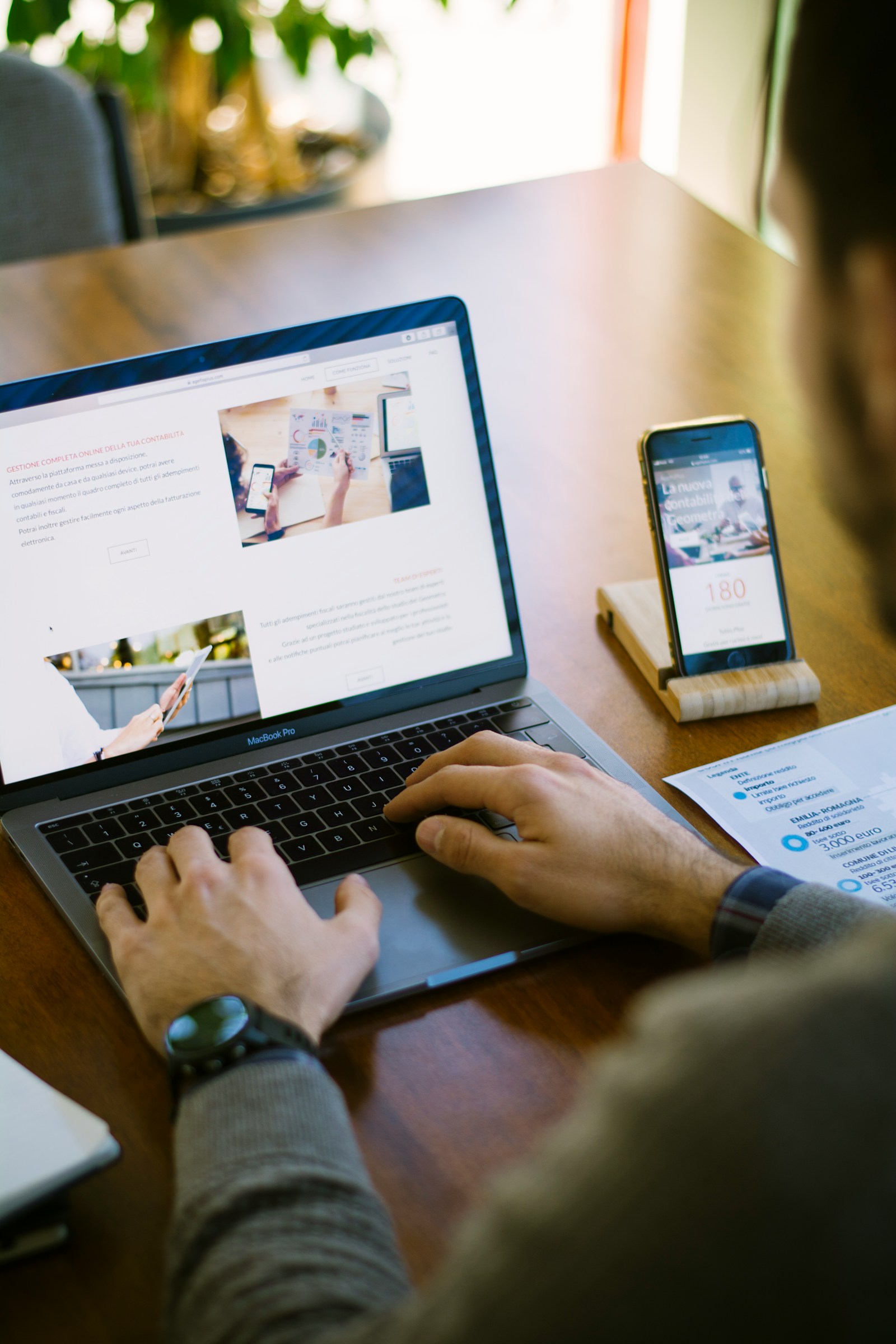 Person som surfar på en webbplats på laptop med mobil bredvid