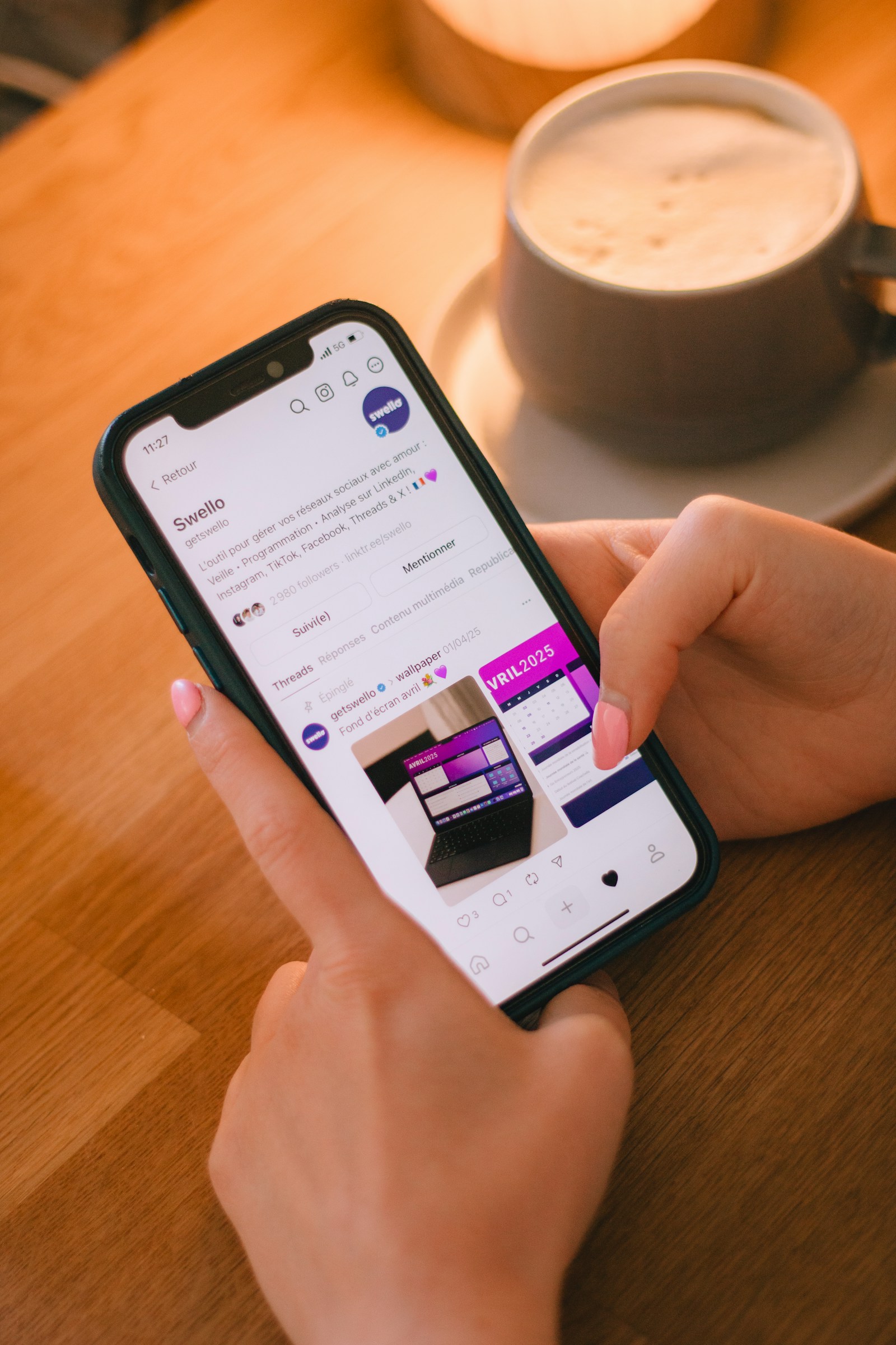 Hand som scrollar på en mobil bredvid en kaffekopp