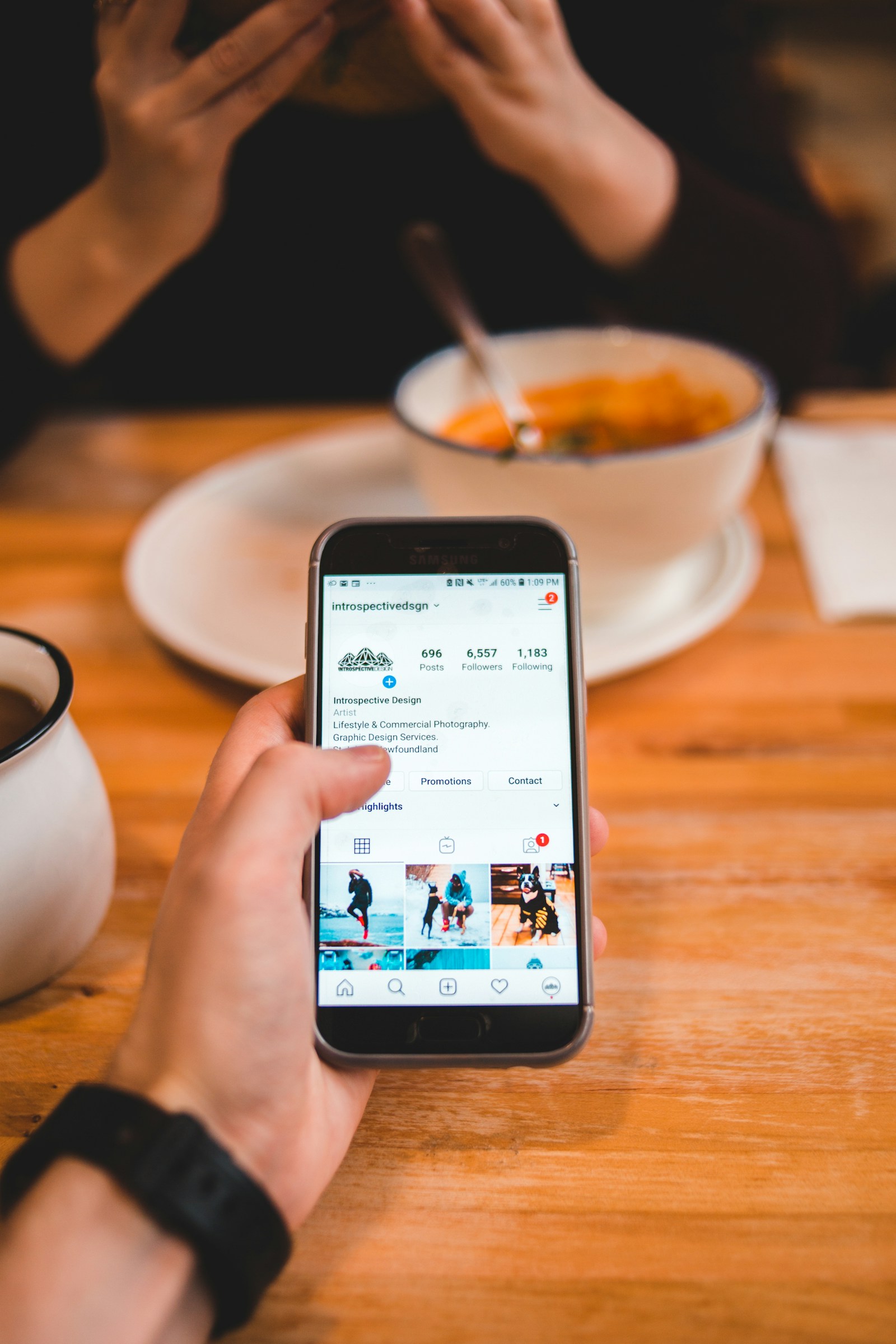 Hand som håller en mobil vid ett restaurangbord