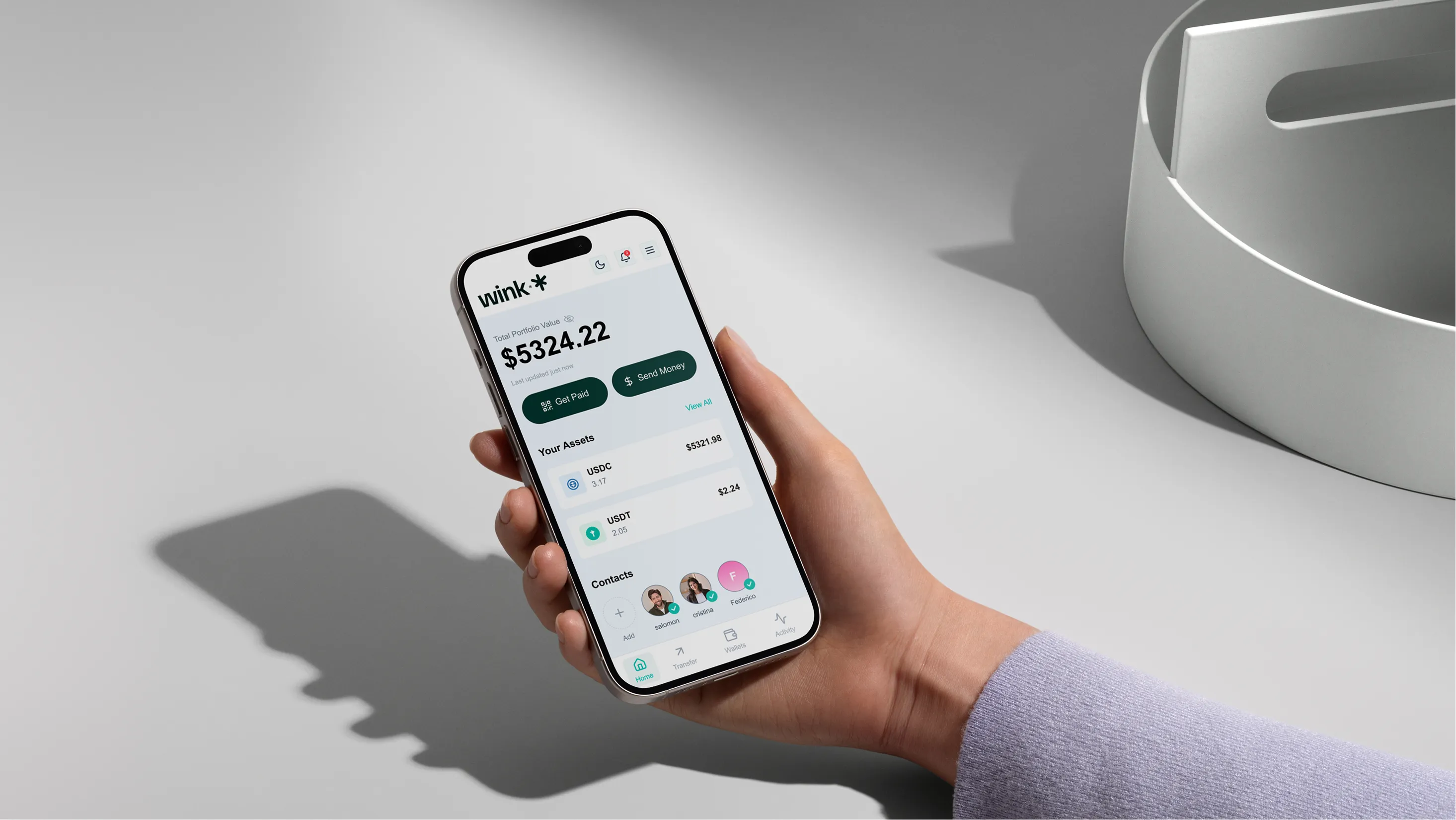 Hand holding a smartphone showing a financial app dashboard with total portfolio value and contacts.