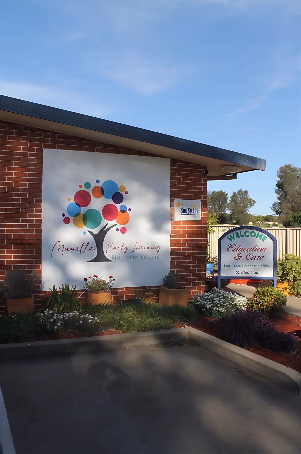 Entrance of Manilla Early Learning center with colorful tree logo and a welcome sign for education and care services.