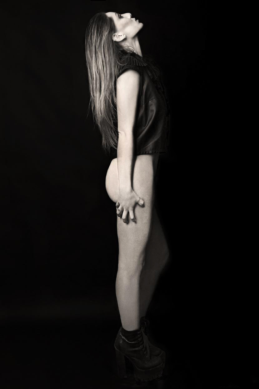 Foto de moda editorial en blanco y negro de una mujer posando de perfil completo, vistiendo un top oscuro y botas de plataforma, con una expresión corporal emotiva.