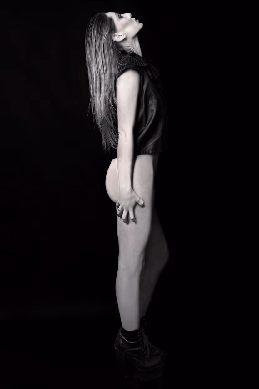 Foto de moda editorial en blanco y negro de una mujer posando de perfil completo, vistiendo un top oscuro y botas de plataforma, con una expresión corporal emotiva.